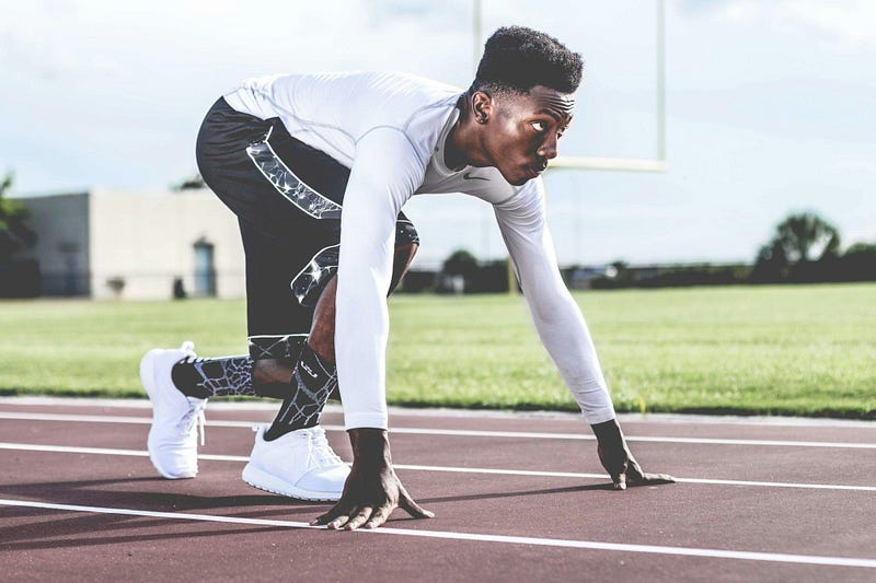 A focused man in starting sprint position getting ready to start running.