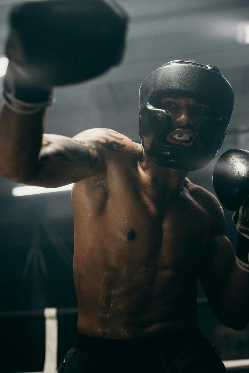 A serious image of a boxer wearing full gear, clenching his teeth whilst mid swing.